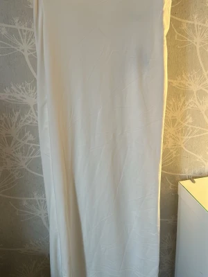 Vit långkjol  - En enkel och stilren vit långklänning i mjukt tyg. Kjolen har en rak passform och bör ingen slit!