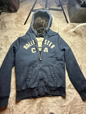 Hollister cardigan fodrad sällsynt  - Väldigt fint skick och en perfekt cardigan att ha nu i de kalla vädret. Den sitter som en M-L kan lösa bild med den på. Tveka inte på att ställa frågor