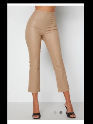 Beige skinnimitation leggings - Snygga beige leggings i skinnimitation med hög midja och croppad längd. Tight passform som framhäver figuren och ger en trendig look. Perfekta att matcha med både toppar och klackar för en cool stil.