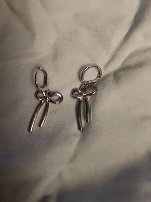 Rosett örhängen - Ett par gulliga rosett örhängen som jag fick men dem är inte riktigt min stil. Dem är silverpläterade och är från glitter. Aldrig använda. 