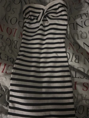 Randig axelbandslös ribbad klänning - Säljer en snygg axelbandslös kortklänning med svartvita horisontella ränder. Klänningen är ribbad och har en tight passform som framhäver figuren. Perfekt för dig som gillar en enkel men trendig look.