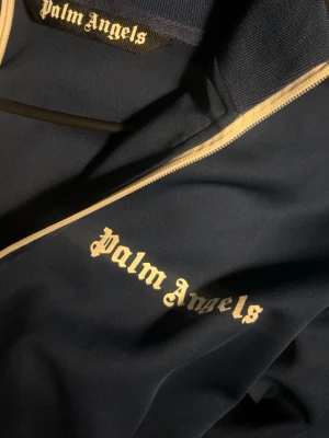 Mörkblå ziptröja från Palm Angels - Snygg mörkblå ziptröja från Palm Angels med vit dragkedja och vita detaljer längs ärmarna. Storlek M! kom privat för mer information!