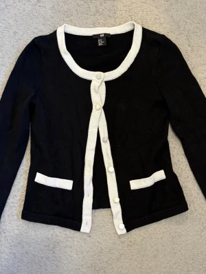 Svart kofta med vita detaljer H&M XS -  Knapparna är målade i silver, men originalfärgen (guld) finns under och färgen går att ta bort med nagellackborttagning 💕💕