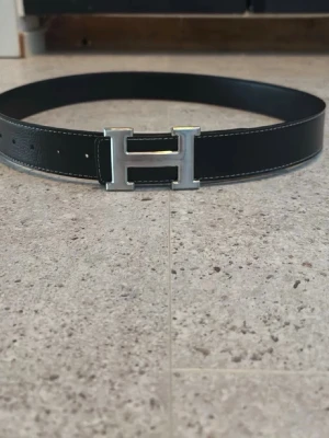 H-bälte - Snyggt bälte med den klassiska silver H spännet och svarta lädret. I ny skick.