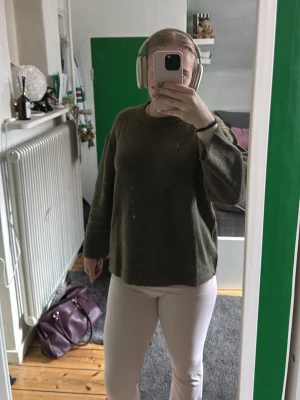 Olivgrön stickad tröja - Mysig olivgrön stickad tröja med avslappnad passform och rund hals. Tröjan har långa ärmar och är tillverkad i ett mjukt, tjockare material som passar perfekt för kyligare dagar. Enkel och stilren design utan synliga loggor eller mönster.