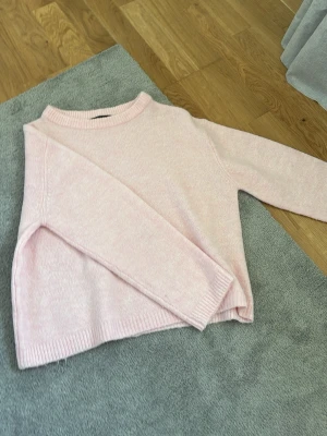 Ljusrosa stickad tröja - Mysig ljusrosa stickad tröja med rund halsringning och ribbade muddar vid ärmslut och nederkant. 