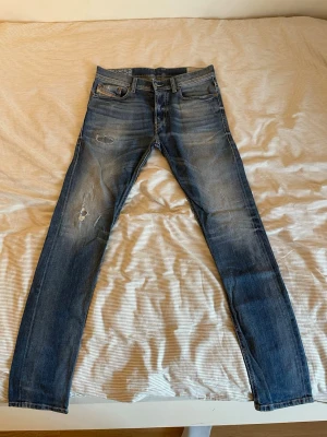 Blå slitna Diesel jeans - Säljer ett par blå  jeans från Diesel med slitningar och hål på låret och knät. Jeansen har klassisk femficksmodell och dragkedjegylf. Perfekta för en avslappnad och trendig look. (W29L31)(Modell: 177cm) 