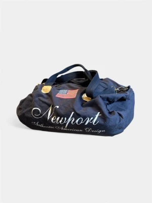 Blå Newport weekendbag med tryck - Snygg marinblå weekendbag från Newport med amerikansk flagga och vit text på framsidan. Väskan har två bärhandtag, detaljer i gult och dragkedja upptill. Perfekt för resor eller gymmet när du vill ha en sportig look.