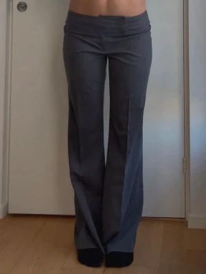 Grå lågmidjade kostymbyxor - Jättesnygga grå, randiga, kostymbyxor med låg midja. Tyvärr är dem lite för stora och lite korta i längden på mig. Jag är 177cm och har vanligtvis S i byxor. 