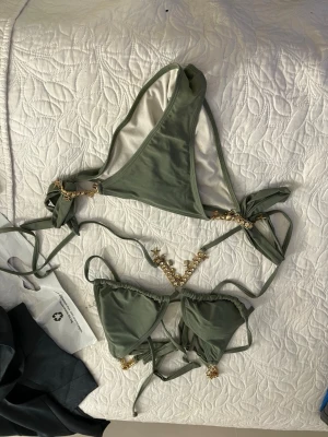 Olivgrön bikini med knyt - Snygg olivgrön bikini med trekantsformad topp och knyt i sidorna. Enkel och stilren design som passar perfekt för lata dagar på stranden eller poolhäng. Materialet känns mjukt och följsamt mot huden.