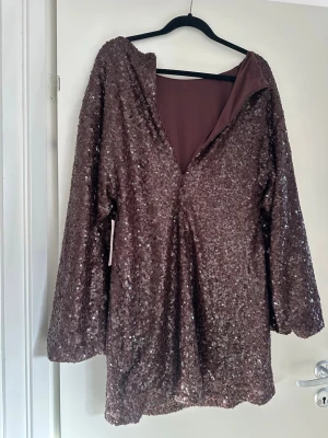 Brun paljettklänning med långa ärmar - Säljer en glittrig brun klänning täckt av paljetter från Nelly! Aldrig använd bara testat. Precis som i nytt skick !  väldigt fin klänning som inte riktigt passade mig, nu hoppas jag att någon annan kan få användning av den. Hör av er vid vidare frågor