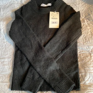 Svart stickad tröja från Zara - Säljer en stickad tröja från Zara med rund halsringning och ribbade muddar. Tröjan har lång ärm  och en tajt passform. 