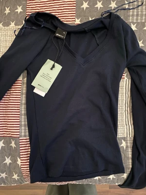 Mörkblå långärmad topp Gina Tricot - Snygg mörkblå långärmad topp från Gina Tricot med v-ringning. Tillverkad i mjuk bomull och har en slim passform som sitter snyggt på kroppen. Perfekt att styla med jeans eller kjol för en clean look.