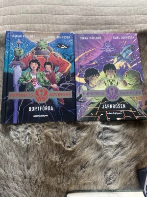 Imperiets arvingar: Bortförda & Järnrosen - Två färgstarka science fiction-böcker i serien Imperiets arvingar av Oskar Källner och Karl Johnsson. Omslagen har tecknade illustrationer med rymdtema, utomjordingar och äventyr. Inbundna böcker med snyggt tryck och futuristisk design. Säljer båda tillsammans för 100 kr!