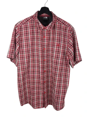 The North Face Casual Rutig Röd Skjorta, L - Rutig kortärmad skjorta från The North Face med knäppning framtill. Skjortan har en klassisk krage och en bröstficka. Baksidan av skjortan har ett ventilerande meshtyg. Armhåla till armhåla: 59cm Axelbredd: 47cm Långt: 75cm