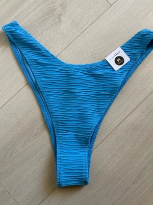 Blå ribbad bikiniunderdel IW - Säljer en blå bikiniunderdel från IW i modellen Even higher lurex rib bottom. Bikinin har en ribbad struktur och hög midja för en trendig look. Perfekt för stranddagar eller poolhäng i sommar.