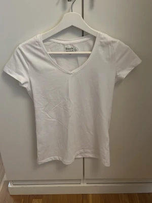 Vit v-ringad t-shirt Basic You XS - Vit t-shirt från Basic You i ekologisk bomull. Modellen har v-ringning och korta ärmar, perfekt för dig som gillar en enkel och clean stil. Passformen är normal och materialet är mjukt och skönt mot huden.