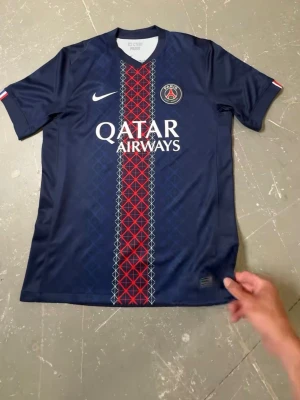 PSG matchtröja blå Nike, Bracola 29! - Snygg blå PSG matchtröja från Nike med röd och vit grafisk rand i mitten, klubbmärke på bröstet, 