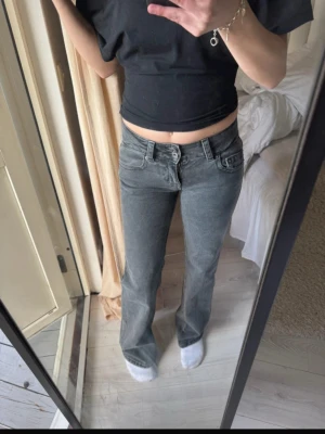  ”baggy” bootcut jeans från Gina Tricot - Säljer ett par grå bootcut jeans från Gina Tricot med låg midja och coola bakfickor med knappdetalj. Jeansen har klassisk femficksdesign och är tillverkade i ett mjukt denimtyg som sitter snyggt på kroppen. Perfekta för en avslappnad och trendig look.  Ej använda bara tvättad ❣️