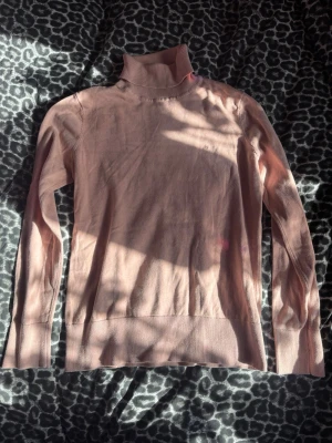 Ljusrosa polotröja  - Säljer en ljusrosa stickad polotröja.  Tröjan har lång ärm, ribbade muddar och hög polokrage. Materialet är tunt och mjukt, perfekt för lager på lager. Storlek S men passar mer xs