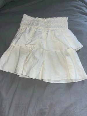 Vit volangkjol från SHEIN - Supersöt vit kortkjol från SHEIN med bred smock i midjan och flera lager volanger. 