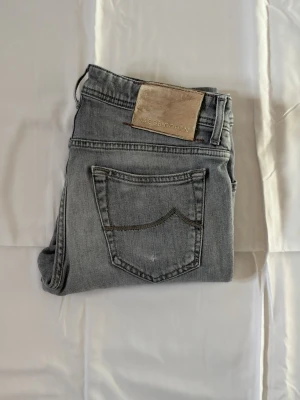 Grå jeans från Jacob Cohen - Snygga grå jeans från Jacob Cohen med klassisk femficksmodell och raka ben. Jeansen har en ljus tvätt och ett läderpatch med logga bak i midjan. Tillverkade i mjukt denimtyg som ger en skön känsla och stilren look.