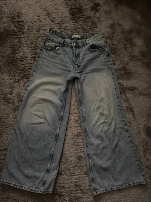 Wide ljusblå jeans från Gina Tricot - Säljer ett par ljusblå jeans från Gina Tricot med breda, raka ben och klassisk femficksmodell. De är mycket oversized! Jeansen har medel låg midja och är tillverkade i 100% bomull. Perfekta för en avslappnad och trendig look.💞 Har lite slitningar nere men det är inget man märker!