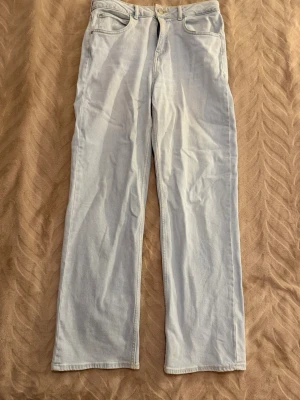 Ljusblå raka jeans från Lee - Säljer ett par ljusblå jeans från Lee med rak passform och klassisk femficksdesign. Jeansen har hög midja och är tillverkade i mjukt denimtyg. Perfekta för en avslappnad och trendig look.