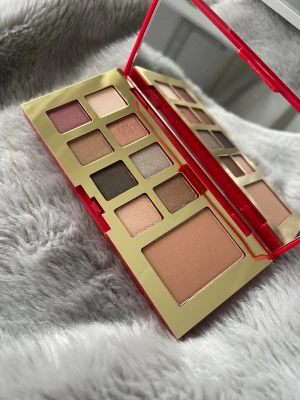 Ögonskuggspalett i rött och guld estee lauder - Snygg ögonskuggspalett med åtta nyanser i rosa, beige, brunt, guld och grått. Paletten har ett stort spegel och ett blush/highlighterfack. Förpackningen är röd med guldigt mönster och känns lyxig och trendig.