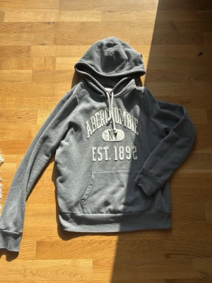 Grå hoodie från Abercrombie - Säljer denna gråa Abercrombie and fitch hoodien, original storleken var i M men då den krympt över tid passar S och XS, riktigt snygg och trendig så den inte säljs längre, hör av er om frågor, jag är 176 och väger 60kg