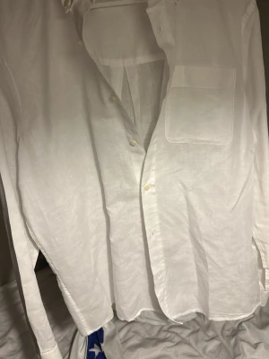 Vit linneskjorta från Zara - Klassisk vit skjorta från Zara i luftigt linne. Skjortan har lång ärm, bröstficka och knappar framtill. Perfekt för en stilren och avslappnad look.