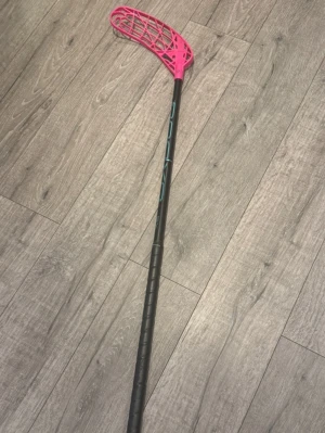 Innebandyklubba Oxdog svart/rosa - Säljer en innebandyklubba från Oxdog med svart skaft och ett rosa blad. Klubban har blå text på skaftet och greppvänligt handtag. Perfekt för dig som gillar innebandy och vill sticka ut med en färgglad klubba. Bladet är lite slitet. 