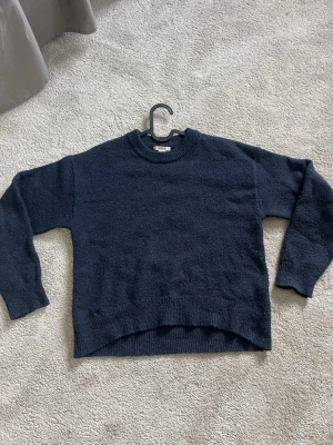 Mörkblå stickad tröja Gina Tricot - Mysig mörkblå stickad tröja från Gina Tricot med rund halsringning. Tröjan är lite nopprig men ändå i bra skick. Storlek 146/152