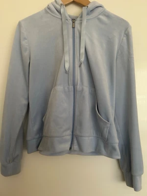 Ljusblått mjukisset - Säljer ett ljusblått mjukisset med hoodie och byxor. Setet är i bra skick men har några små defekter. Hoodiens snöre är lite slitet i ena änden (se bild) och byxorna saknar snöret i midjan. Annars är setet helt och fint.  Storlek: Hoodien är i M och byxorna i XS.