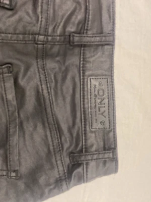 Svarta coated jeans från ONLY XS - Snygga svarta coated jeans från ONLY i storlek XS. Jeansen har en glansig finish som ger en cool look och klassiska fickor både fram och bak. Perfekta för dig som vill ha ett par trendiga och bekväma byxor med lite edge.