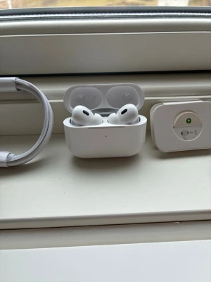 Apple AirPods Pro 2 - Säljer ett par vita Apple AirPods Pro med trådlöst laddningsetui. Hörlurarna har en stilren och kompakt design med silikonproppar för bra passform. Perfekta för musik, samtal och träning. USB-C laddkabel medföljer.
