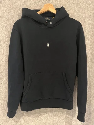 Polo Ralph Lauren Hoodie - Säljer denna jättefina hoodie från Pilot Ralph Lauren i Navy blue färg. Perfekt nu inför våren , står M på insidan men är kort på mig som är 185-186 så skulle säga att den är S. obs saknar snören men annars fin! Skriv gärna vid intresse