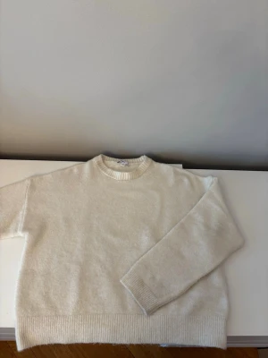 Vit stickad tröja från subdued - Klassisk vit stickad tröja med rund hals och ribbade muddar. Tröjan har en avslappnad passform och är tillverkad i en mjuk ullmix som känns skön mot huden. Perfekt att matcha med jeans för en enkel och stilren look.