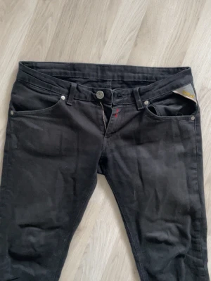 Svarta slim fit jeans från replay - Säljer ett par svarta skinny fit jeans från Replay Jeans med klassisk femficksmodell och knappgylf. Jeansen har en diskret logga på fickan och är tillverkade i mjukt denimtyg med lite stretch för extra komfort.