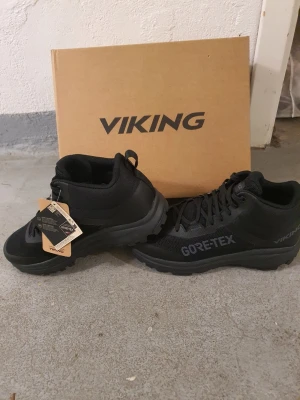 Svarta Viking Gore-Tex kängor - Helt nya. Snygga svarta kängor från Viking med Gore-Tex-membran som håller fötterna torra. Skorna har en sportig design, grov sula för bra grepp och är tillverkade i slitstarkt syntetmaterial. Perfekta för dig som gillar att vara aktiv och vill ha stilrena kängor. Dubbskor