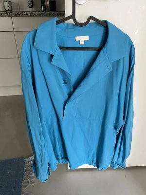 Blå jacka från COS med krage - Säljer en ljusblå vårjacka från COS med avslappnad passform och bred krage. 