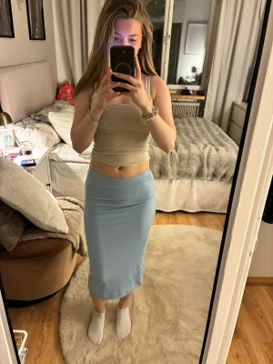 Ljusblå långkjol i mjukt material - Säljer en ljusblå långkjol med enkel och slimmad passform. Kjolen är tillverkad i ett mjukt och stretchigt material som sitter bekvämt och följer kroppen. Perfekt för dig som gillar stilrena plagg med en fräsch färgton.