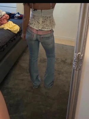 Ljusblå bootcut jeans - Säljer ett par ljusblå bootcut jeans med klassisk femficksdesign och låg midja. Jeansen har en avslappnad passform och är tillverkade i denim med lätt tvättad look. Perfekta för en casual och trendig stil.