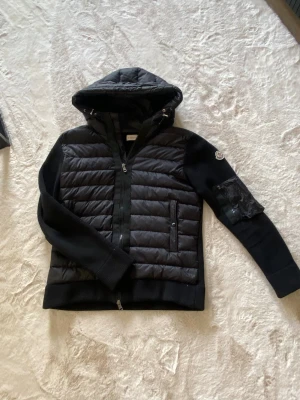 Svart moncler cardigan  - Tjena säljer nu min äkta moncler jacka då den inte används längre, haft den ca 2-3 år men är fortfarande i bra skick, är också intressant att byta mot moncler väst. Storklek S men passar mig som har M.                                                                               Mvh Hampus