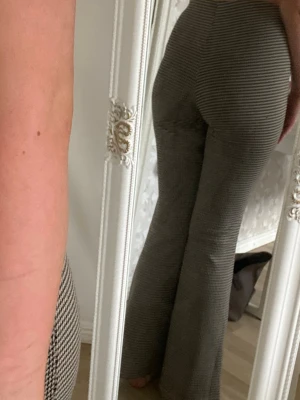 Bruna utsvängda leggings med mönster - Snygga bruna leggings med svartvitt småmönster och utsvängda ben. Hög midja och stretchigt material som sitter tajt upptill och släpper nedtill. Perfekta för dig som gillar retrovibbar och vill ha något bekvämt men ändå trendigt. Passar på mug som är 170. 