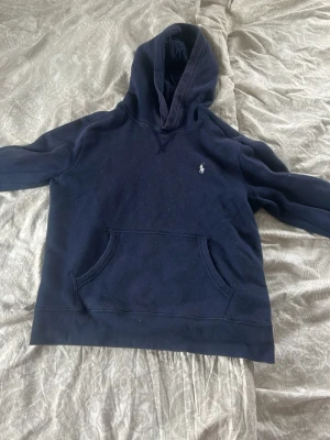 Mörkblå hoodie från Polo Ralph Lauren - Snygg mörkblå hoodie från Polo Ralph Lauren med klassisk huva och magficka. Ikoniska lilla loggan broderad på bröstet. Perfekt för en chill och avslappnad stil. Mjuk bomullskänsla och skön passform.