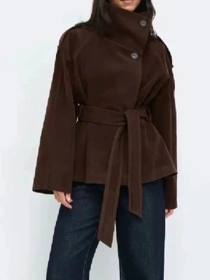 Brun kappa slutsåld från Gina  - Stilren brun kappa med hög krage och stora knappar framtill. Kappan har ett matchande knytband i midjan och vida ärmar. Perfekt för dig som vill ha en klassisk och trendig look. Materialet ser ut att vara mjukt och ger en lyxig känsla. Prislapp kvar