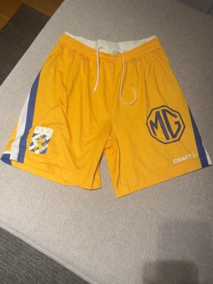 IFK Göteborg x Craft matchshorts - Gula sportshorts från Craft med IFK-logga och blå-vita ränder på sidorna. Shortsen har resår och dragsko i midjan. Perfekta för träning eller match. Tillverkade i lätt och snabbtorkande material. Hör av dig vid funderingar eller med prisförslag 🤩