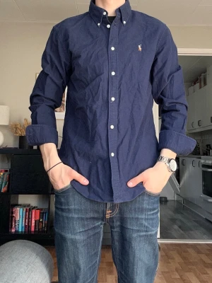 Polo Ralph Lauren Skjorta - Polo Ralph Lauren | Skjorta | Classic Fit | Medium | 399kr | Mörkblå | Mycket Bra Skick |      Axelbredd: 42cm Längd: 65cm              Skickas inom 24h📦        Kontakta vid minsta fråga eller fundering
