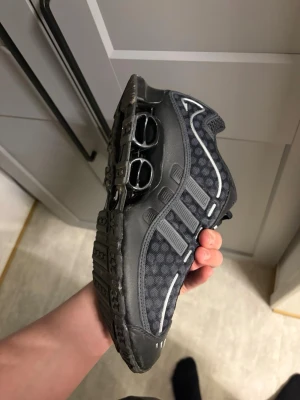 Svarta adidas  sneakers - Adidas sneakers i svart med grå detaljer och vita linjer. Skorna har en unik Shox-sula med fjädrande pelare och meshmaterial på ovansidan för extra ventilation. Snygga och sportiga med klassisk adidas-design och låg profil.